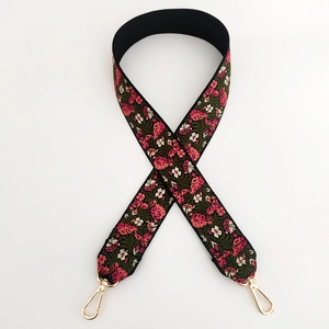 Close-up of vintage floral embroidery on wide strap with gold metal lobster clasps