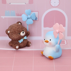 Detail of resin bear and penguin figurines holding small windmills in a pink room set
