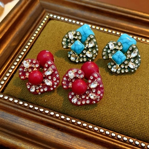 Macro view of vintage earrings with red beads and turquoise stones on green fabric