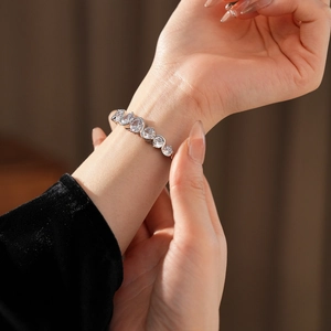 Detail of silver bangle with wave zircon stones on wrist against black velvet