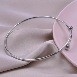 Detailed macro view of minimalist silver stainless steel open bangle with double metal balls