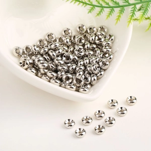 Macro view of polished 18K gold-plated spacer beads in a heart-shaped ceramic bowl