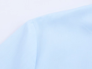 Close-up of light blue woven fabric texture and stitching details on a long-sleeve shirt