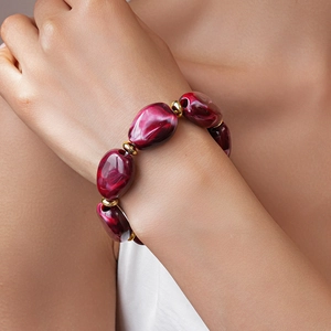Close-up of chunky red marble resin beads with gold metal spacers on a wrist