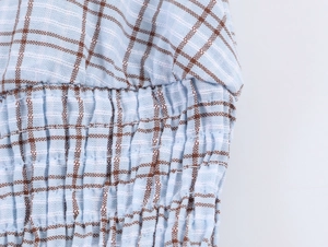 Macro view of blue plaid fabric showing elastic smocking texture and fine stitching detail