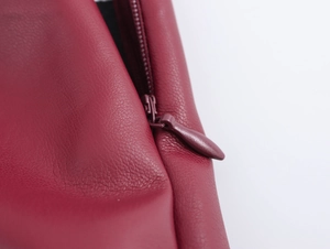 Gros plan sur la texture du cuir synthétique rouge et le détail de la fermeture éclair