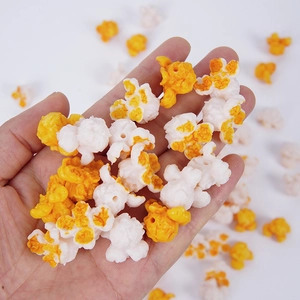 Hand holding a realistic 1:1 scale resin popcorn kernel model with yellow and white texture