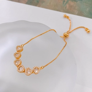 Détail d'un bracelet réglable plaqué or avec six breloques en forme de cœur en zircon