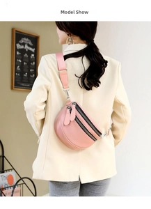 Close-up of pink crescent crossbody bag with double zippers worn by model in beige suit