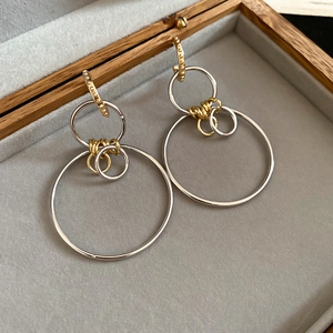 Detailed shot of two-tone geometric layered hoop earrings in a wooden jewelry box