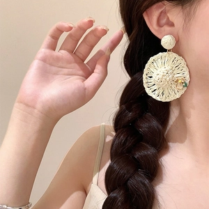 Böhmische Raffia-Strohhut-Ohrringe mit zarten beigen Blumenakzenten am Model getragen