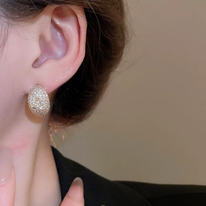 Close-up of a gold crescent moon earring with pavé zircon crystals on a female model