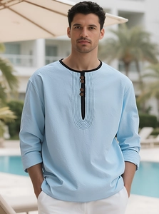Detail of light blue linen Henley shirt featuring three-button collar and pleated chest design