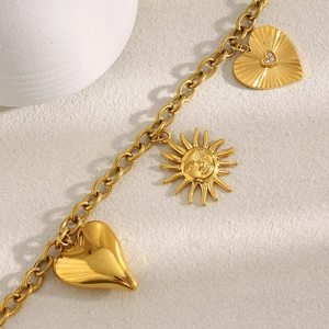 Detailed macro view of 18K gold plated chain with heart and sun-shaped charms