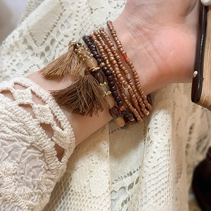 Close-up of bohemian multi-layer beaded bracelets with brown tassels and metallic accents