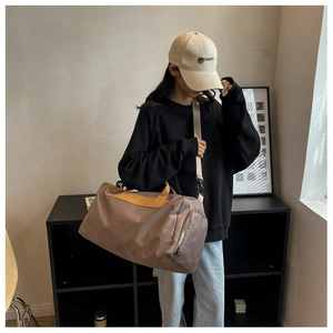 Mocha gym bag with shoulder strap shown in a minimalist indoor setting with a lifestyle model
