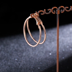 Detailed view of large rose gold hoop earrings on a vintage display stand