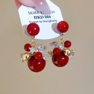 Macro detail of red zircon firework drop earrings with 925 silver needles and gold plating