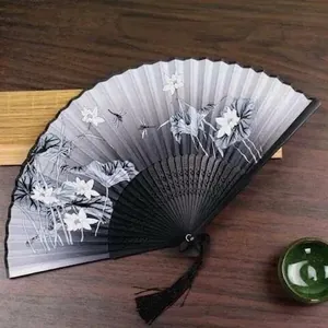 Detail of traditional Chinese folding fan with lotus pattern, dragonfly and black silk tassel