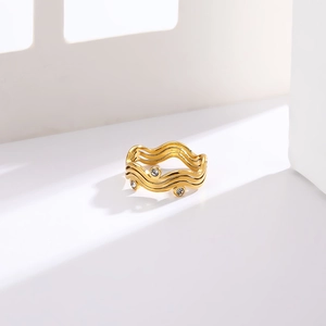 Macro detail of wave-shaped stainless steel gold ring with inlaid clear zircons