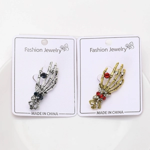 Detail of vintage skull hand brooches with rhinestones in silver and gold metal finishes