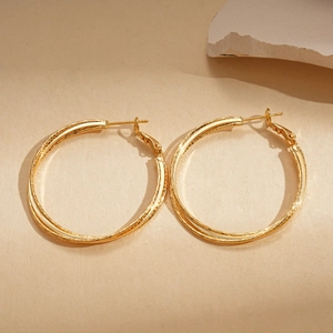 Detail of 18k gold plated double layered hoop earrings on warm beige background