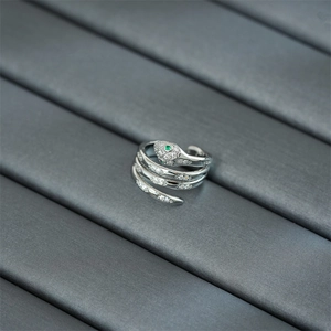 Macro shot of silver snake ring with sparkling zircons and distinctive green gemstone eyes