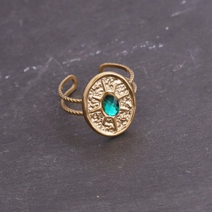 Gros plan d'une bague dorée rétro sertie d'une pierre précieuse verte ovale facettée