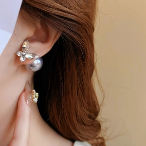 Vue détaillée d'une boucle d'oreille papillon argentée avec zircon et perle violette