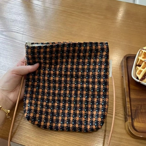 Close-up of the thick tweed plaid fabric texture and zipper detail of the crossbody bag