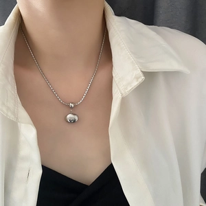 Minimalist silver bead necklace with pebble-shaped pendant on a female model