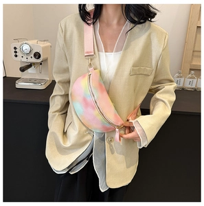 Fashionable rainbow tie-dye waist bag with gold zippers shown on a model in a beige blazer