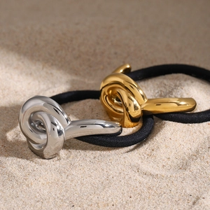 Minimalist U-shape 18k gold and silver stainless steel hair ties on a sandy beach