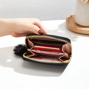 Mini black plush purse with gold zipper, pompom charm and pink multi-slot interior