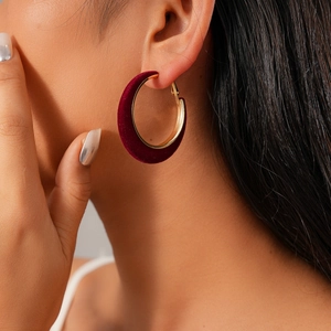 Close-up of model wearing a large burgundy velvet and 18K gold-plated hoop earring