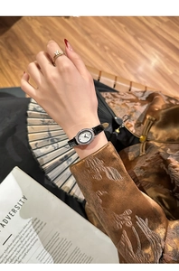 Macro detail of oval crystal watch with black leather strap on a vintage background