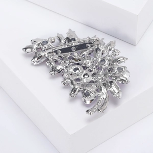Macro detail of silver alloy brooch back featuring secure rotary safety pin and hollowed structure