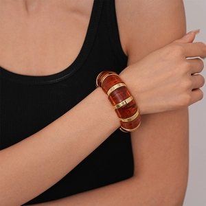 Macro shot of amber acrylic elastic bracelet with metallic edges and marbled patterns