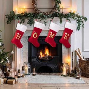 Set di quattro calze di Natale in velluto rosso con ricamo HOME su un camino festivo