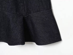 Close-up of deep blue denim dress hem featuring detailed ruffles and twill texture