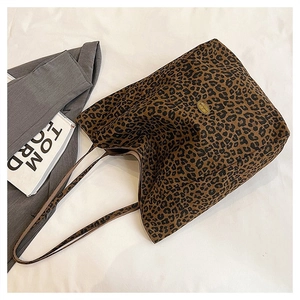 Detail of leopard print tote bag featuring a gold metal logo on a canvas texture