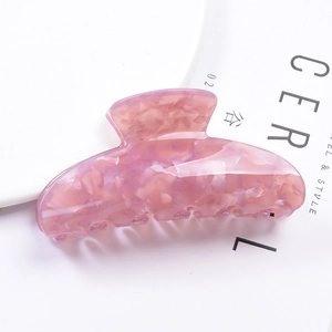 Detailed top view of pink marble texture acrylic hair claw clip on a book background