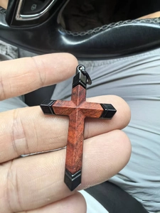 Détail du pendentif croix en bois brun-rouge avec bords de cadre en métal noir