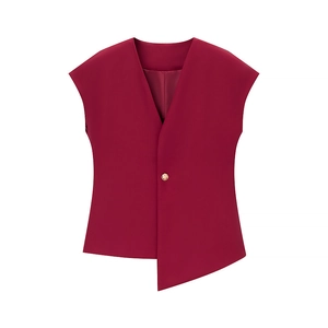 Detail of burgundy sleeveless vest featuring an asymmetrical hem and single gold button