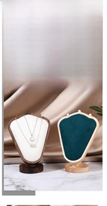 Detail of luxury velvet necklace display stand with walnut wood base and green padded bust