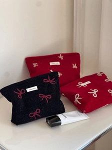 Detailed embroidery of bow patterns on red and black fabric vanity pouch set