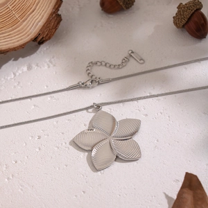 Detail of silver floral pendant necklace with snake chain on a natural wooden background