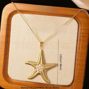 Macro shot of gold starfish pendant with pearl center on beige fabric tray