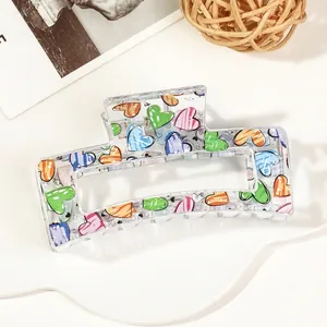 Detail of transparent hair claw clip with colorful hand-painted heart patterns