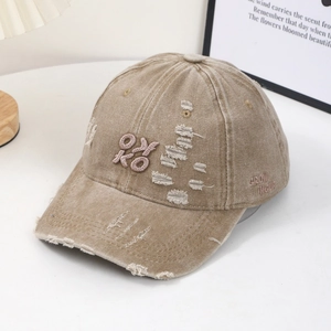 Vintage khaki distressed baseball cap with pink embroidery in a warm indoor setting